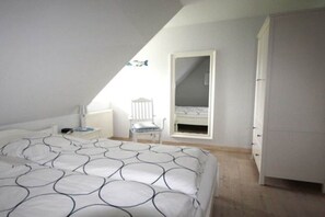 Een slaapkamer met een bed, een stoel, een kledingkast en een raam.