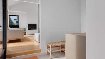 A modern, minimalist living space with a large window, a sofa, a television, and a wooden bench.
