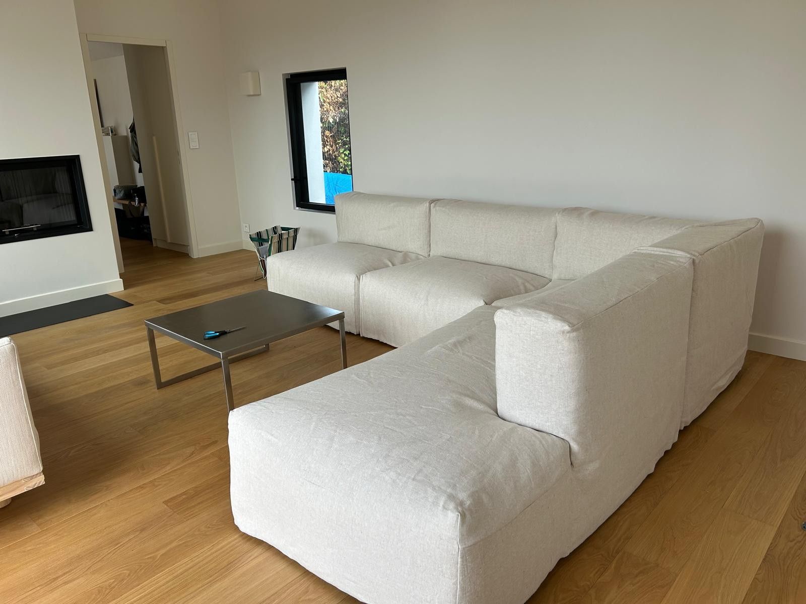 Ein modernes Wohnzimmer mit einem Ecksofa, einem Couchtisch und einem an der Wand befestigten Flachbildfernseher.