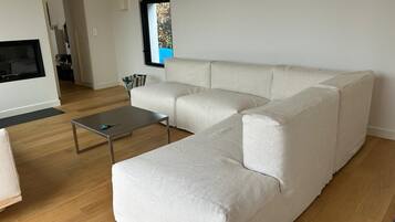 Ein modernes Wohnzimmer mit einem Ecksofa, einem Couchtisch und einem an der Wand befestigten Flachbildfernseher.