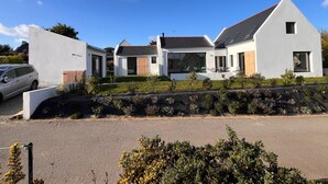 Uma casa moderna de dois andares, com telhado inclinado, amplas janelas e um gramado bem cuidado.