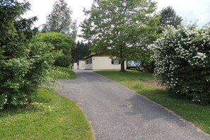 Ein Weg führt zu einem Gebäude, umgeben von üppigem Grün und blühendem Buschwerk.