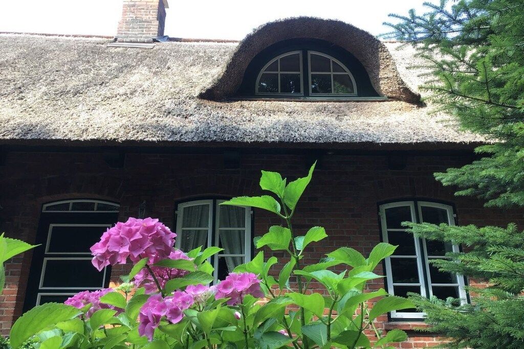A brick building with a thatched roof and a window with a curved top.