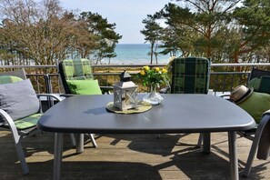 Eine Terrasse im Freien mit Tisch und Stühlen, mit Blick auf ein Gewässer.