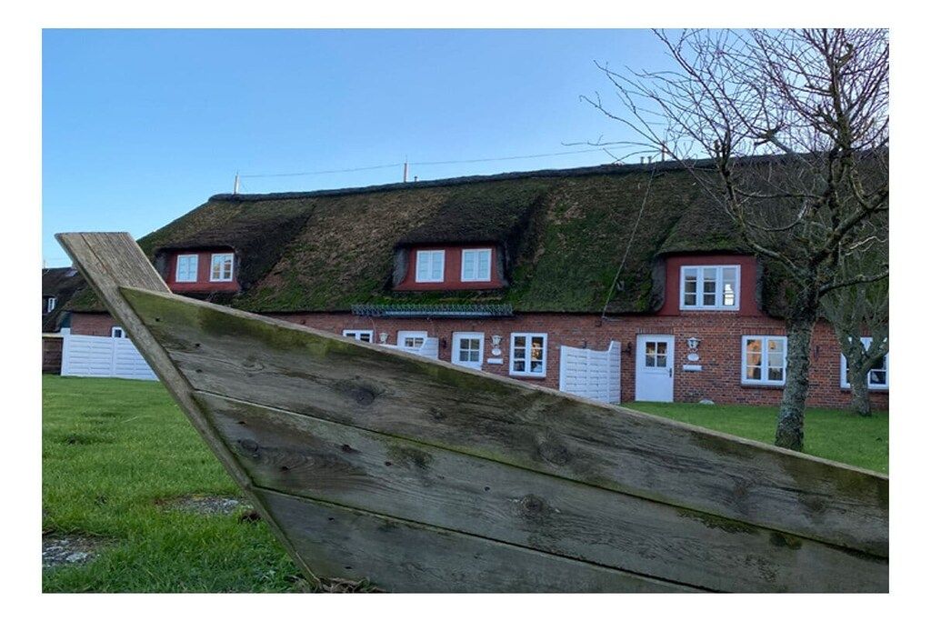A brick building with a thatched roof and multiple windows.