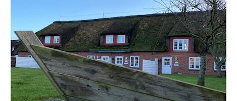 A brick building with a thatched roof and multiple windows.