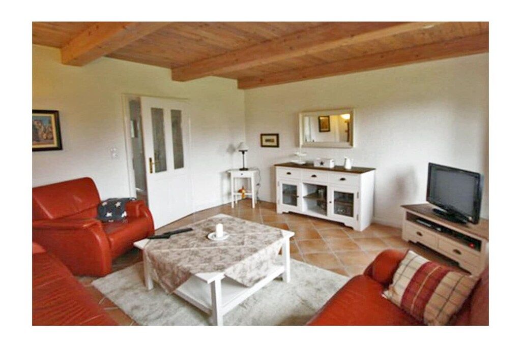 Ein Wohnzimmer mit einer Couch, einem Couchtisch, einem Fernseher und einem Schrank.