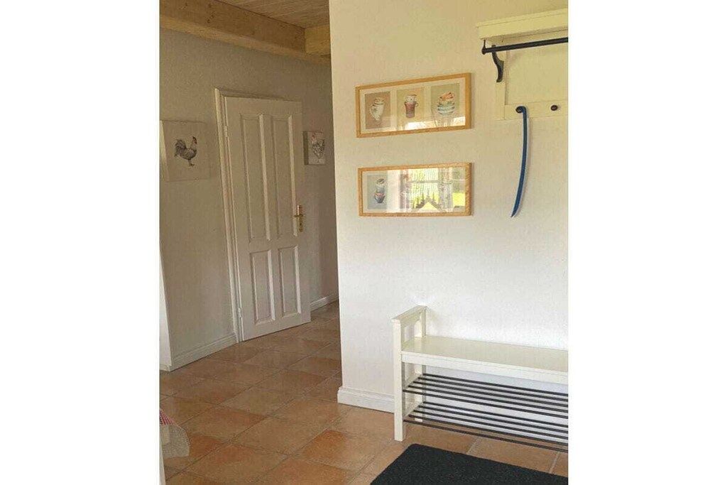 A hallway with a white bench, framed pictures on the wall, and a door.