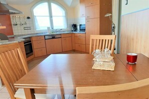 Eine Küche mit Holzschränken, einem Esstisch und Stühlen.