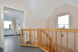 A room with a wooden staircase, a window, and a door leading to another room. - Holiday home with 3 bedrooms (Breege\/ Juliusruh OT Breege)