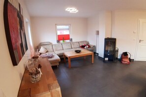 A living room with a sofa, a coffee table, a fireplace, and a painting on the wall. - Holiday home with 3 bedrooms (Breege\/ Juliusruh OT Breege)