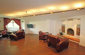 Ein geräumiges Wohnzimmer mit Ledersofas, einem Kamin und einem flachbildfernseher an der Wand.