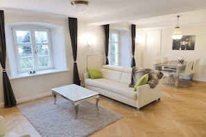 A modern living room with a sofa, coffee table, and dining area. - Holiday apartment with 1 bedroom (Bastorf OT Hohen Niendorf)