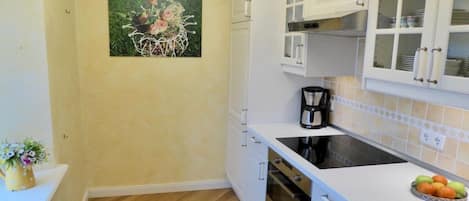 A kitchen with white cabinets, a black stove, and a coffee maker.