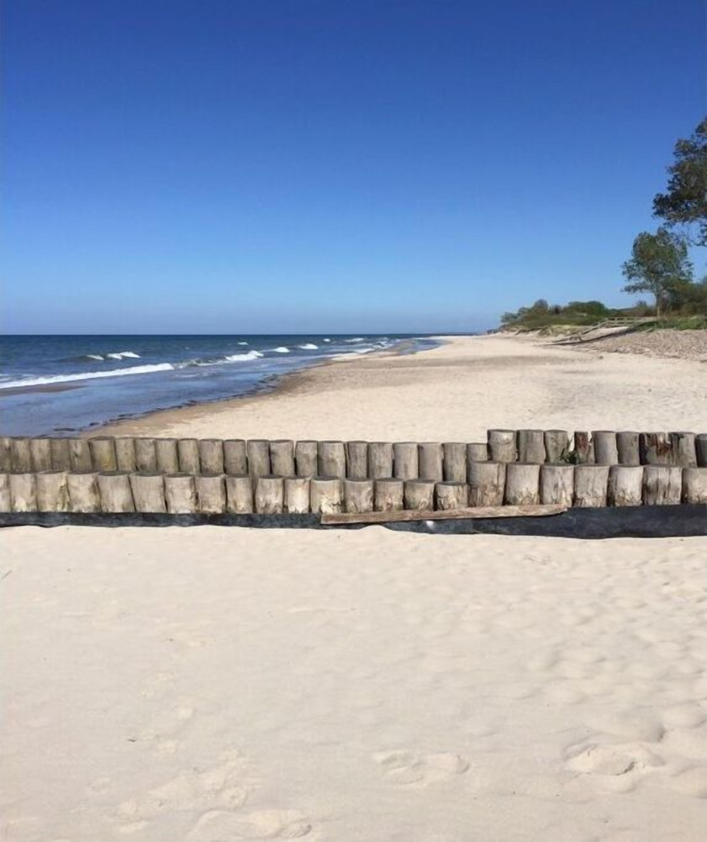 A sandy beach with a wooden fence and ocean waves.