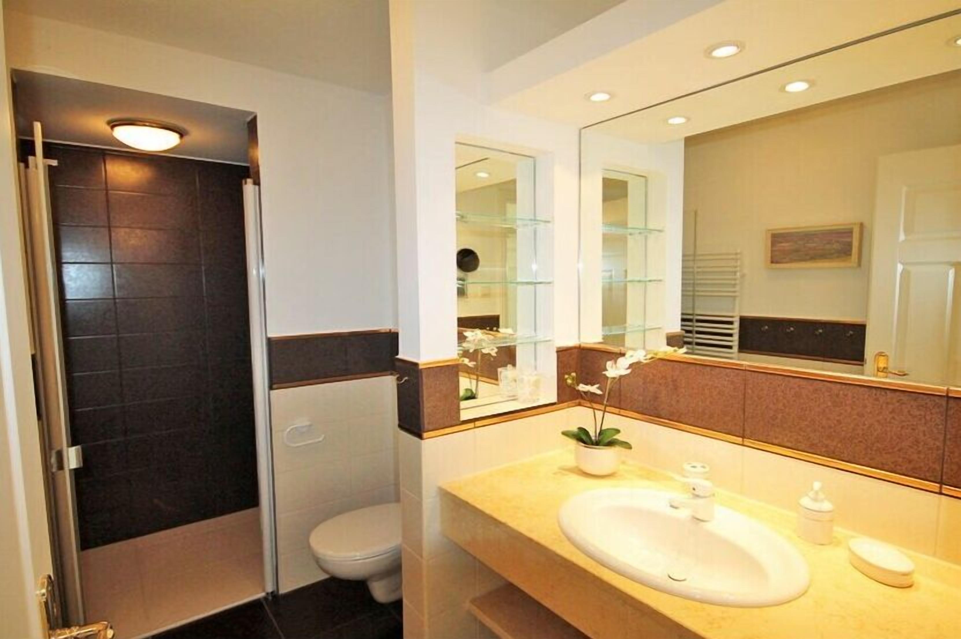 A modern bathroom with a shower, toilet, and sink.