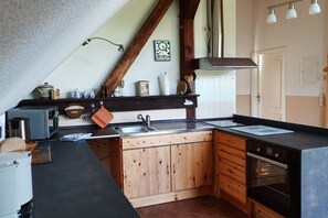 A kitchen with wooden cabinets, a black countertop, a sink, and a stove. - Holiday apartment with 2 bedrooms (Rietz-Neuendorf, OT.Neubrück)