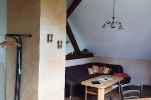 A room with a dark leather sofa, a wooden table, and a hanging light fixture. - Holiday apartment with 2 bedrooms (Rietz-Neuendorf, OT.Neubrück)