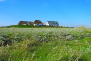 A coastal property with two white houses on a grassy hill, overlooking the sea. - in the Engler holiday home (Högel)