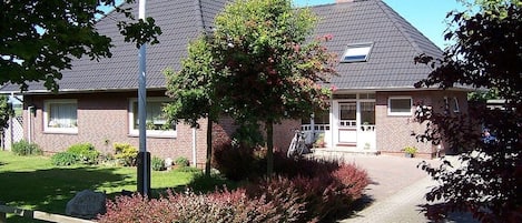 A residential house with a brick facade, a sloped roof, and a paved driveway.