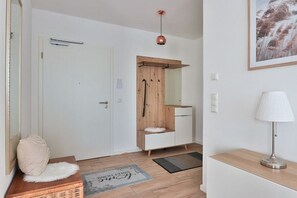 A room with a white door, a wooden cabinet with a mirror, a white lamp, and a framed picture on the wall. - Holiday apartment in Bad Doberan with balcony (Bad Doberan)