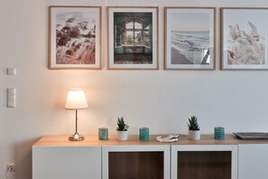A room with a white cabinet, a lamp, and four framed pictures on the wall. - Holiday apartment in Bad Doberan with balcony (Bad Doberan)