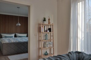 A bedroom with a bed, a bedside shelf with decorative items, and a window with sheer curtains. - Holiday apartment in Bad Doberan with balcony (Bad Doberan)