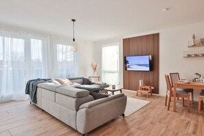 A modern living room with a sofa, a dining table, and a television. - Holiday apartment in Bad Doberan with balcony (Bad Doberan)