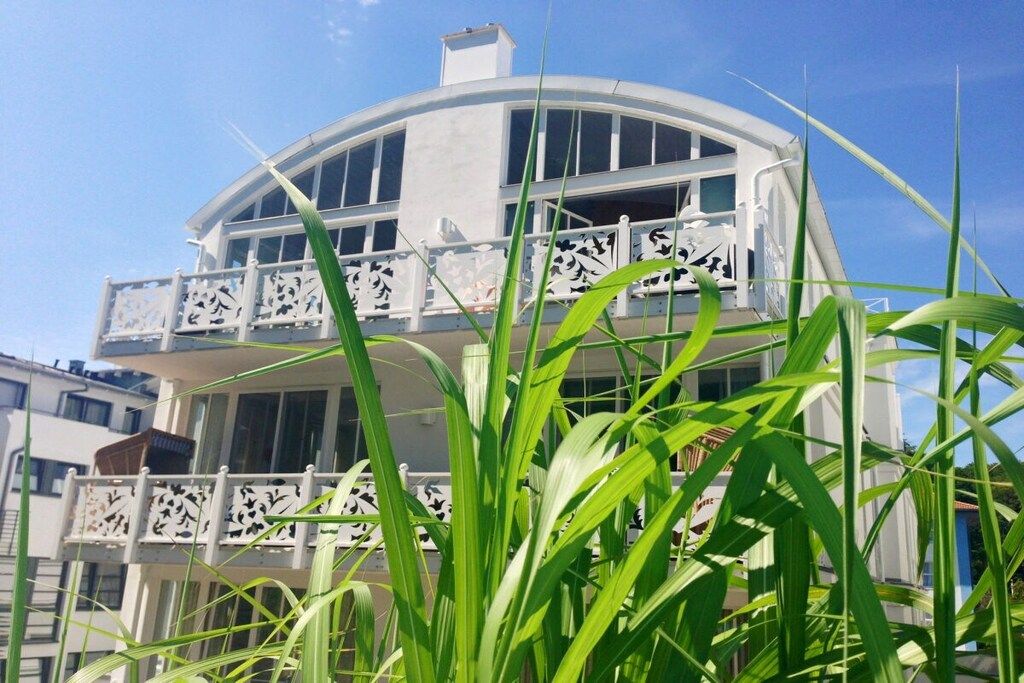 A multi-story building with balconies, surrounded by greenery.