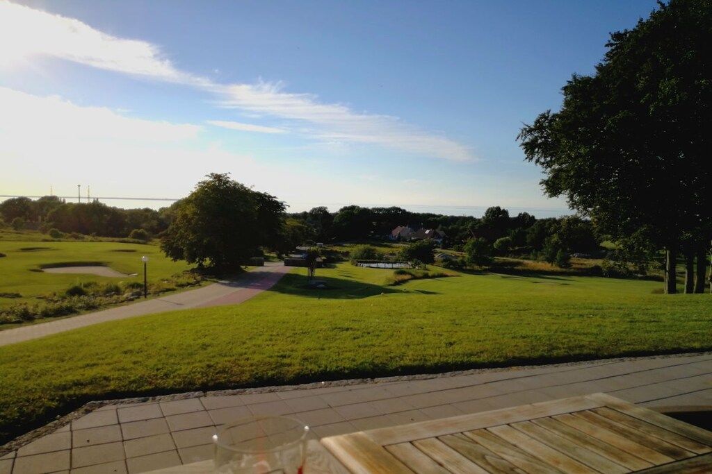 A golf course with a clear sky, a walking path, and a wooden deck area.