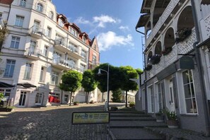 Eine Kopfsteinpflasterstraße mit Gebäuden, einem Schild für 'FahrraD' und blauem Himmel.
