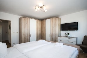 A hotel room with a large bed, a flat-screen TV mounted on the wall, and a wooden wardrobe. - Holiday apartment with 1 bedroom (Sassnitz auf Rügen)