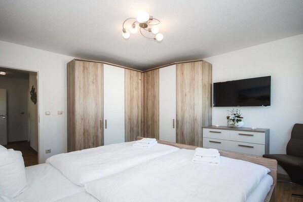 Ein Hotelzimmer mit einem großen Bett, einem flachbildfernseher an der Wand und einem Holzschrank.