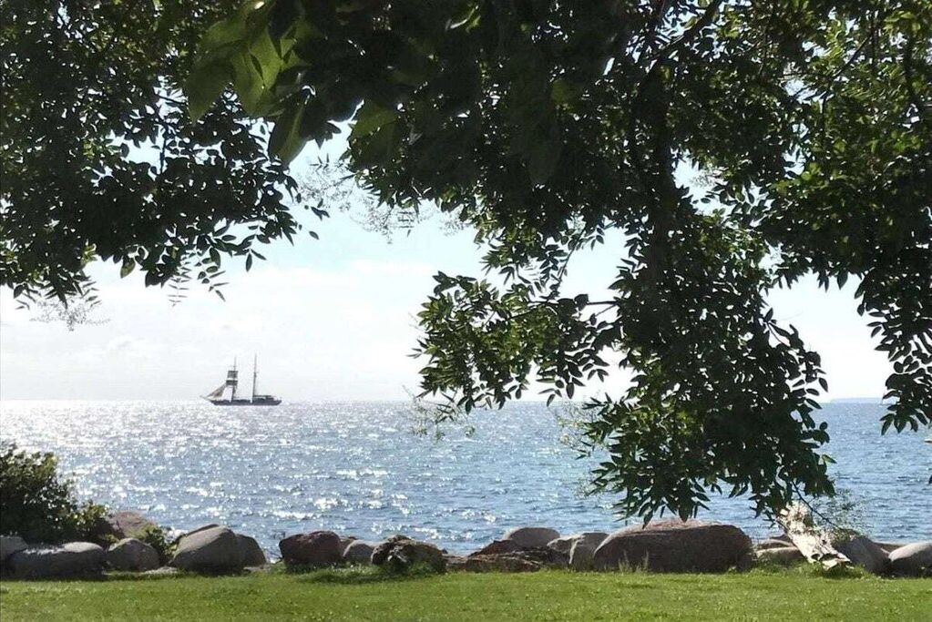 Eine Küstenlandschaft mit einem Schiff in der Ferne, umgeben von Felsen und viel Grün.
