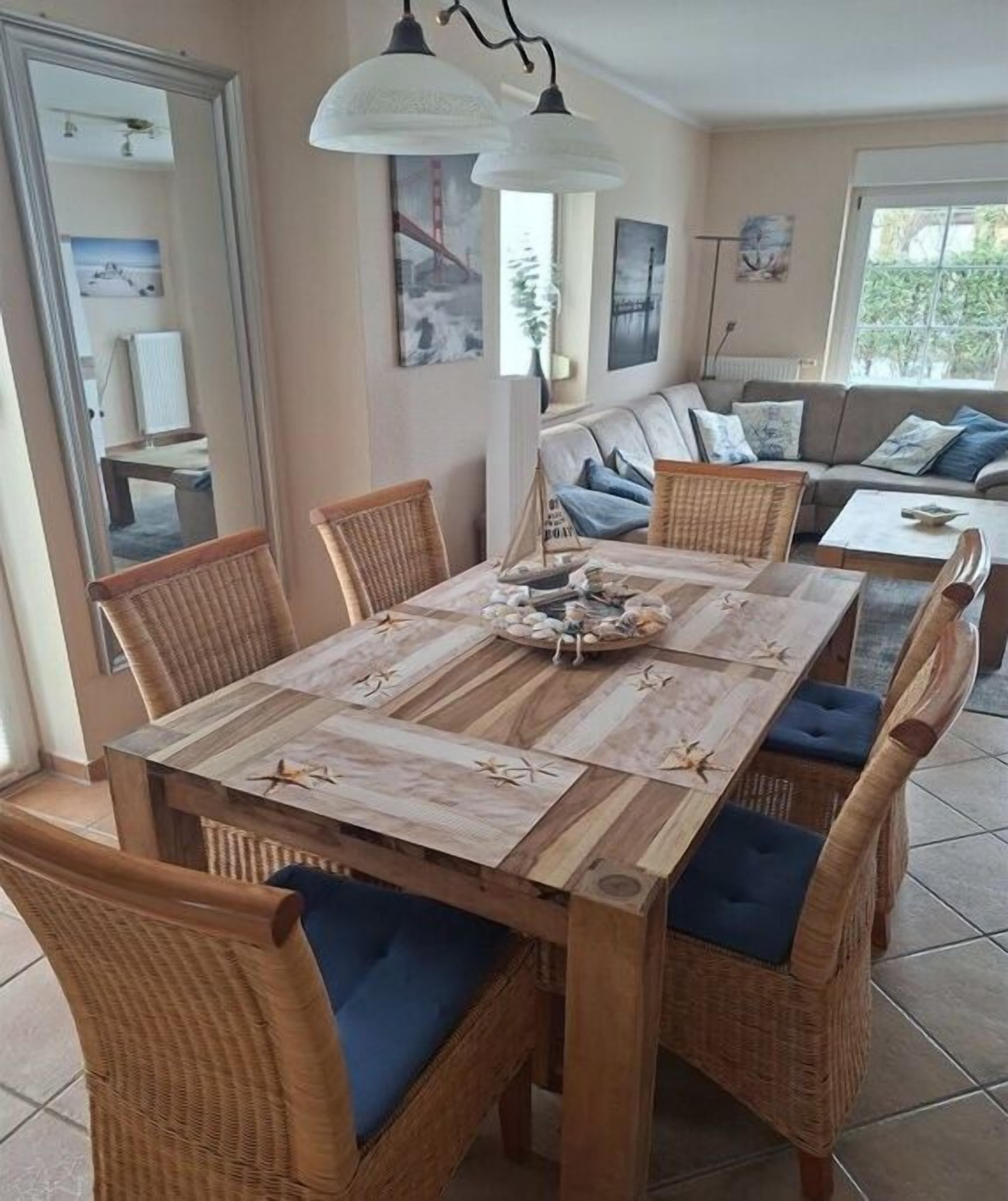 Un comedor con una mesa de madera, sillas de mimbre y un sofá al fondo.