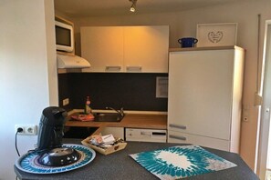 A compact kitchenette with a microwave, a coffee maker, a sink, and a refrigerator. - Holiday apartment with 2 bedrooms (Scharbeutz\/Haffkrug)