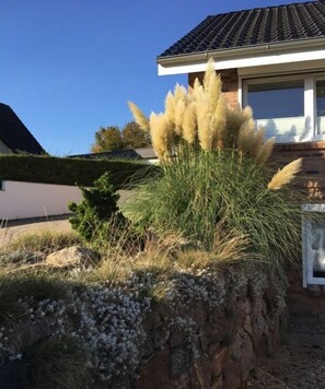 Ein Haus mit einem Ziegeldach, einem gepflegten Rasen und einem Felsen mit Vegetation.