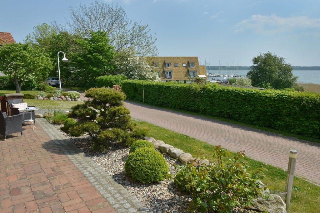 A paved pathway leading to a building with a view of a body of water and boats.