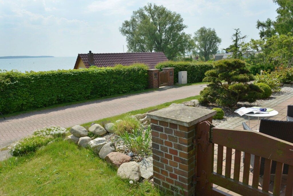 A residential property with a paved driveway, a brick wall, a wooden gate, and a view of the sea.