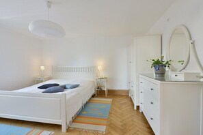 Ein Schlafzimmer mit einem Bett, Nachttischen, einer Kommode, einem Spiegel und einer Pendelleuchte.