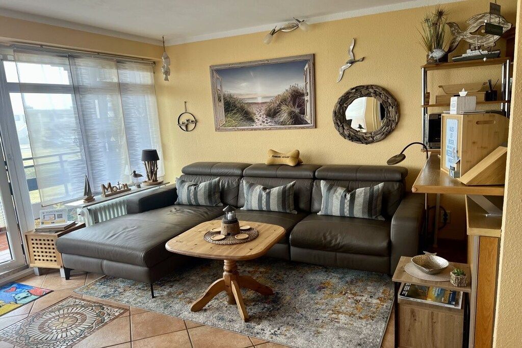 A living room with a sectional sofa, a coffee table, a painting, and a mirror on the wall.