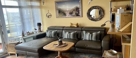 A living room with a sectional sofa, a coffee table, a painting, and a mirror on the wall.