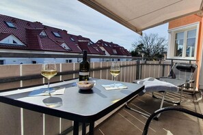 A balcony with a table, two glasses of white wine, a bottle of wine, and a bowl of snacks. - Holiday apartment with 1 bedroom (Zingst)