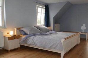 A bedroom with a bed, bedside table, lamp, window, and a wall with a silhouette decoration. - Holiday apartment with 1 bedroom (Zingst)