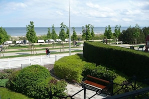Un parque con bancos, una cerca blanca y vistas al mar.
