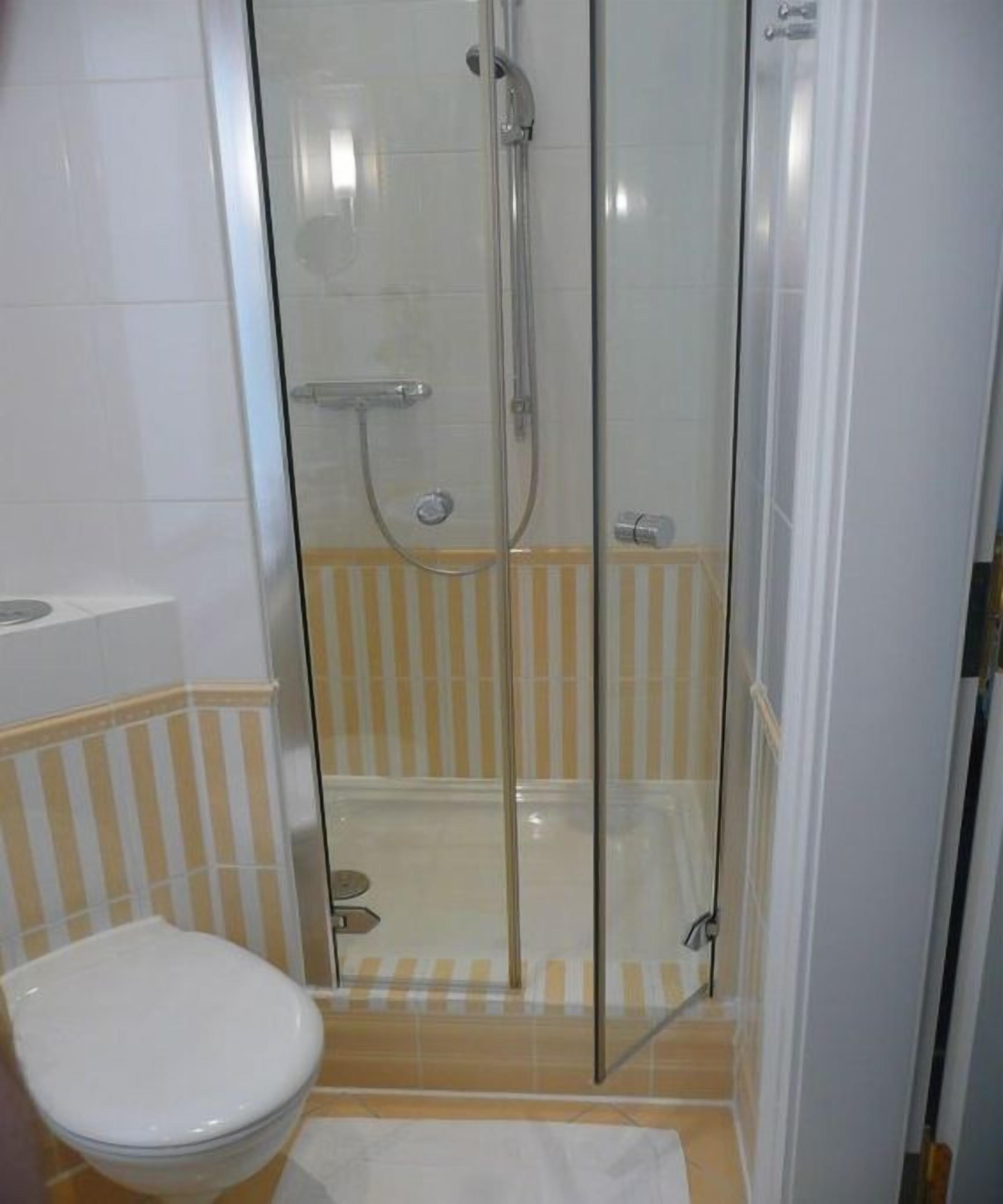 Ein Badezimmer mit einer Duschkabine, einer Toilette und einem Streifenboden.