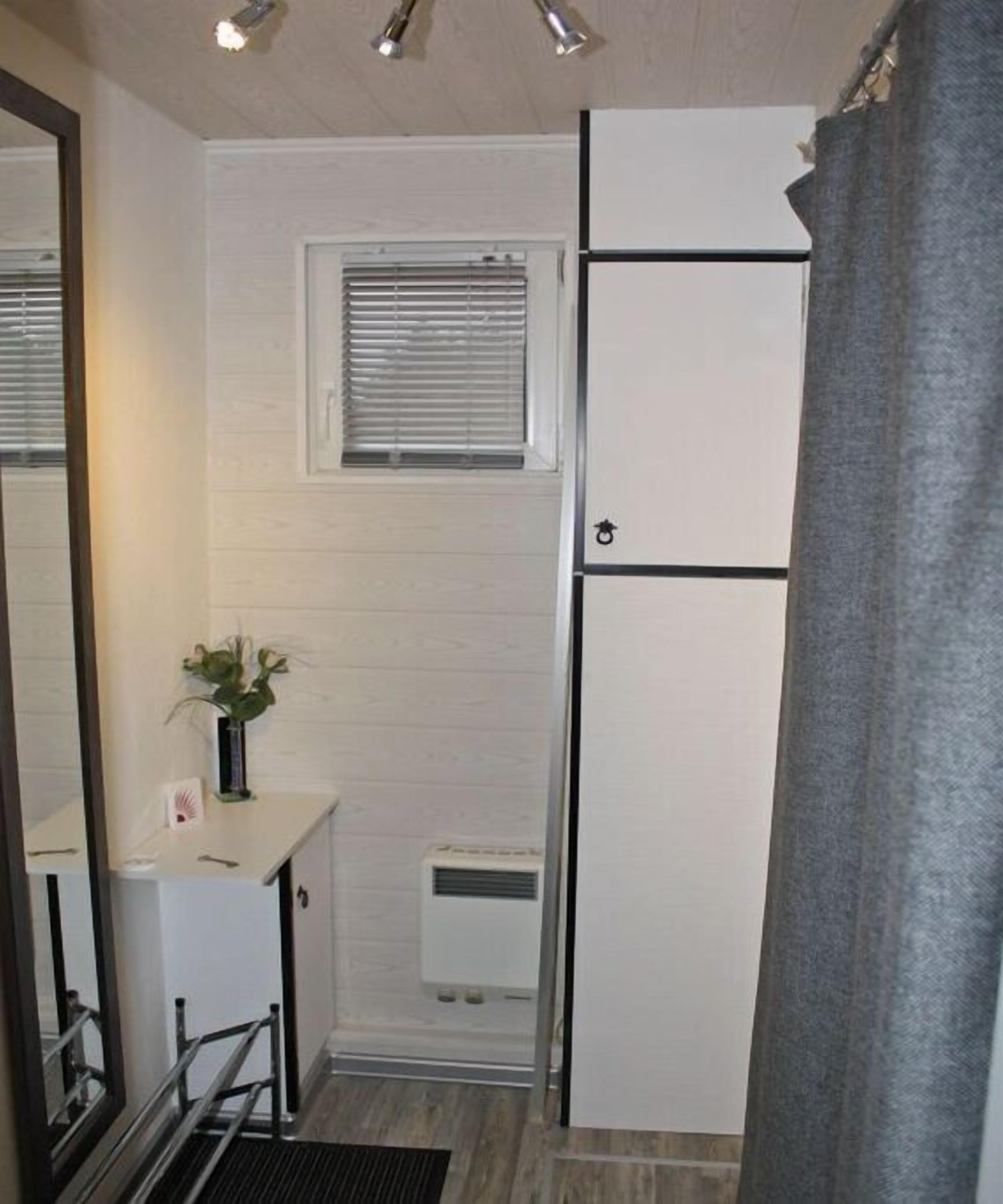 Eine kompakte Küche mit einem eingebauten Kühlschrank, einer kleinen Arbeitsfläche und einem Fenster mit Jalousien.