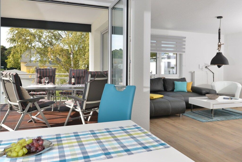 A modern living space with a dining area, a sofa set, and a view of the outdoors.