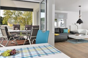 A modern living space with a dining area, a sofa set, and a view of the outdoors. - Holiday apartment with 2 bedrooms (Breege\/Juliusruh OT Juliusruh)