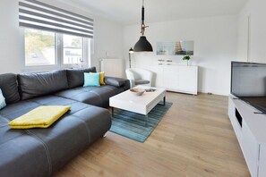 A modern living room with a leather sofa, a white coffee table, and a television. - Holiday apartment with 2 bedrooms (Breege\/Juliusruh OT Juliusruh)